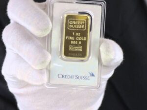 a hand holding a credit suisse gold bar